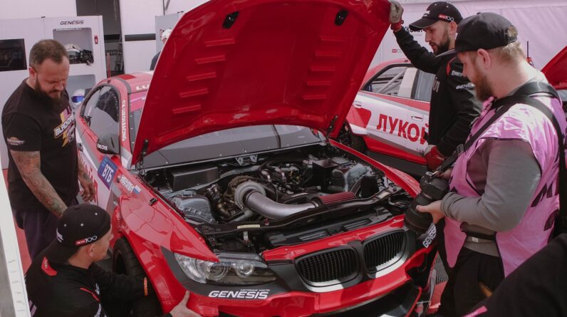 a group of men working on a red car