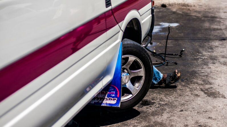 a man sitting on the ground next to a parked car