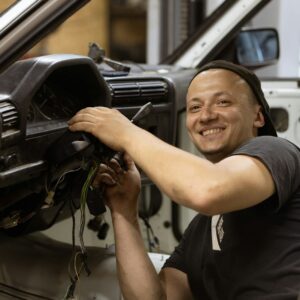 man in black crew neck t-shirt holding black car steering wheel